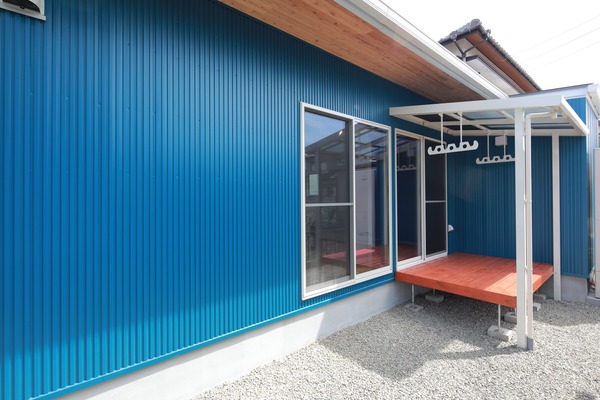 青×白の爽やかな外壁に赤色のかわいいウッドデッキが付いた自然素材のお家 画像